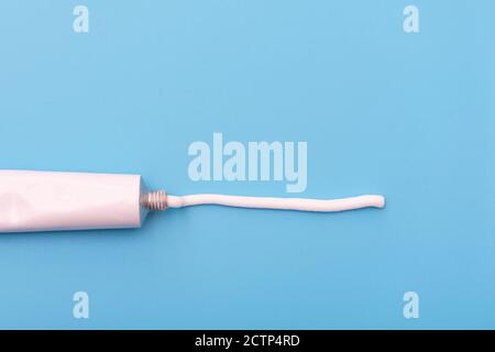 Tube with white cream or ointment blue background Stock Photo