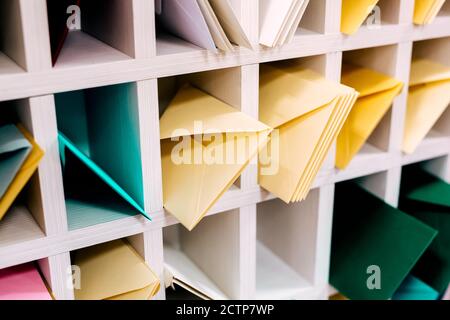Various sort mail envelopes arranged on a shelf by color and type categories. Stock Photo