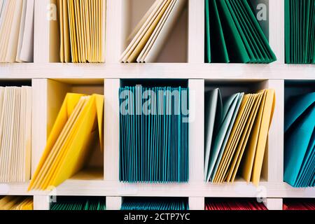 Various sort mail envelopes arranged on a shelf by color and type categories. Stock Photo