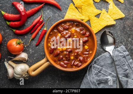 Chili con carne. Mexican food with beans in pot on black table. Top view. Stock Photo