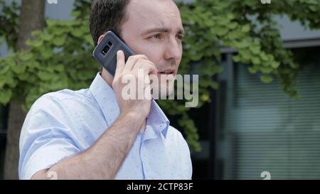 Handsome young man walking and talking on the phone. Stock Photo
