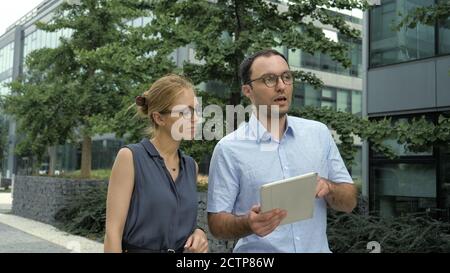 Female and Male Business People Walking Talking and Using Tablet Stock Photo