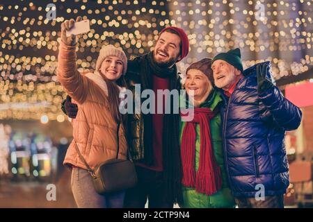Photo of full family four members x-mas gathering senior grandparents children telephone make selfie show v-sign outerwear hat scarf coat generation Stock Photo