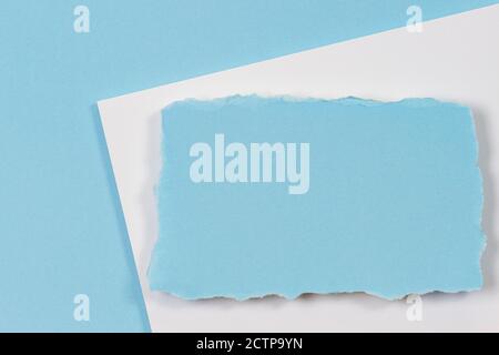 Blank blue ripped piece of paper, torn paper card on white and light blue background. Top view Stock Photo