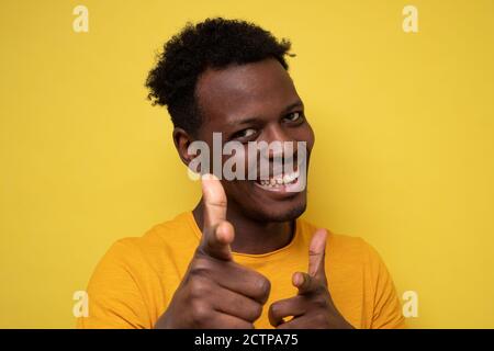 Funny young african man smiling happily and pointing his index fingers at camera Stock Photo