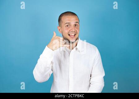Russian business man over blue background smiling doing phone gesture with hand and fingers like talking on the telephone Stock Photo