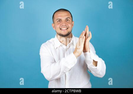 Russian business man wearing white shirt standing over blue background clapping and applauding happy and joyful, smiling proud hands together Stock Photo