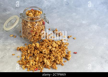 Homemade granola with strawberry slices in a glass jar. On a gray background. Vegetarian dish. Healthy breakfast. Copy space. Stock Photo