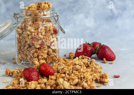 Homemade granola with strawberry slices in a glass jar. On a gray background. Vegetarian dish. Healthy breakfast. Copy space. Stock Photo