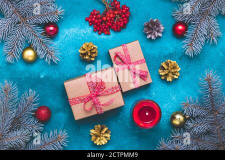 Christmas tree with gifts on a blue background. Happy New Year composition with red and gold balls, fir branches, a burning candle, viburnum berries. Stock Photo