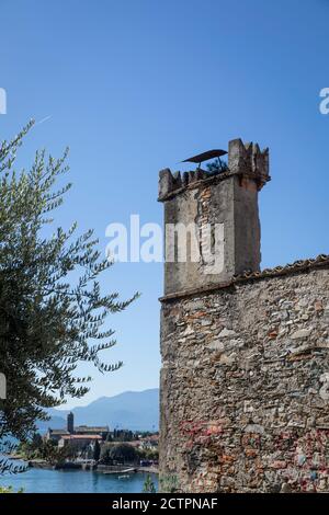 Ancient stone house wall (part brick and stone and partially rendered) with chimney on top and views of Gravedona beyond and its position alongside La Stock Photo