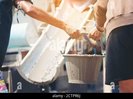 Construction workers helped cement bucket loaders to be introduced into a points set. Stock Photo