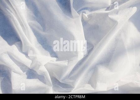 white rippled textured fabric background illuminated by the rays of the sun. Luxurious background design  Stock Photo