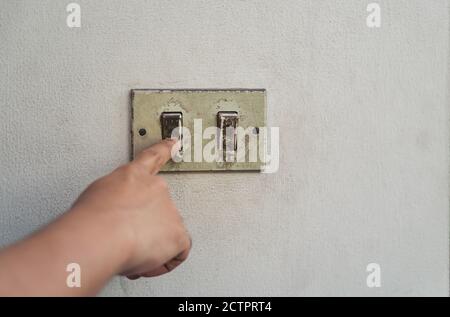 Hand turning the old electrical switches off. Power on/off switches. danger Stock Photo
