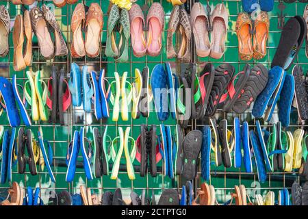 UK, London, Camden Town, 12 September 2020.Multicolored sandals, flip flops and other shoes hanging on the fence Stock Photo