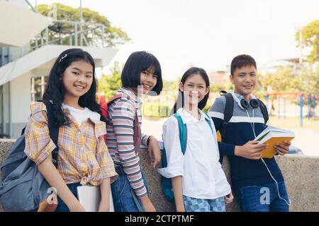 Portrait of School kids with backpacks smiling standing in elementary school hallway Stock Photo
