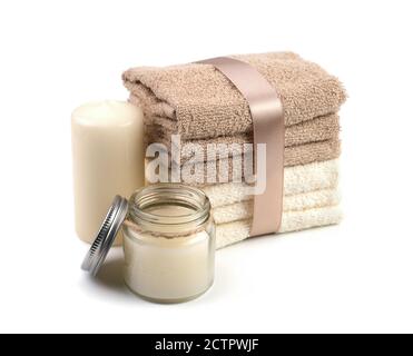 Spa set of beige and white towels tied with a satin ribbon, candles and cream, on a white background. Stock Photo