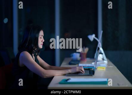 Pretty business woman working alone in dark office, workhard she close eye Stock Photo