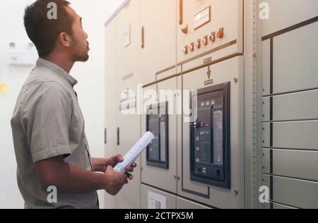 Electrical engineer man checking voltage and test at the Power Distribution Cabinet in the control room, preventive maintenance Yearly Stock Photo