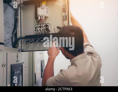 Electrical engineer man checking voltage and test at the Power Distribution Cabinet in the control room, preventive maintenance Yearly Stock Photo