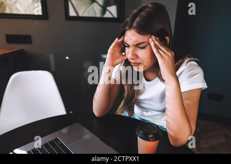 Woman working at office with laptop, suffering from chronic daily headaches Stock Photo