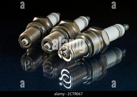The Spark plug for car on black background. Detail rests upon glass table with reflection Stock Photo