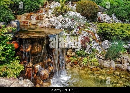 Small artificial waterfall in man made tropical garden Stock Photo