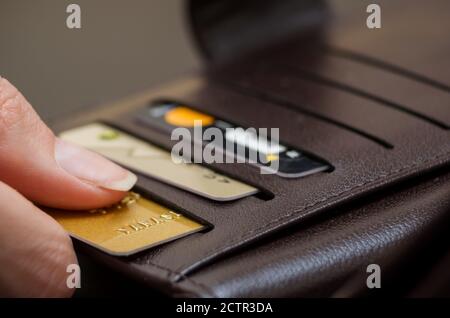 Women's hand pulls out a credit card from a black purse Stock Photo