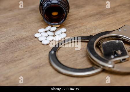 Handcuffs, flask and pills on a black background. The concept of medicine and expertise Stock Photo