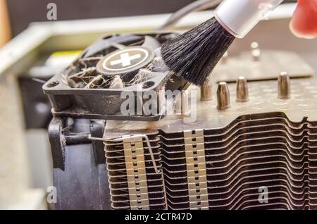 Dust on computer PC CPU cooler. Cleaning the computer cooler with a red brush. concept of maintenance of the main components of the computer Stock Photo