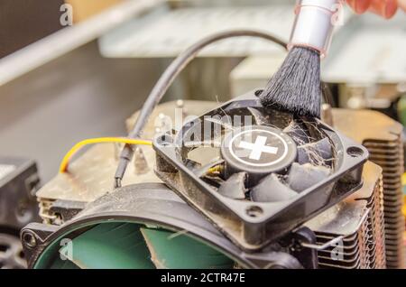 Dust on computer PC CPU cooler. Cleaning the computer cooler with a red brush. concept of maintenance of the main components of the computer Stock Photo