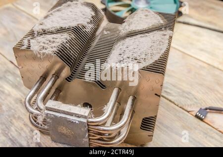 Dirty dusty radiator computer processor close-up on a wooden table. concept of cleaning parts of the computer Stock Photo