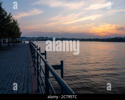 Helsinki / Finland - September 24, 2020: A beautiful sunset on the river bank with calm waters on a summer night. Stock Photo