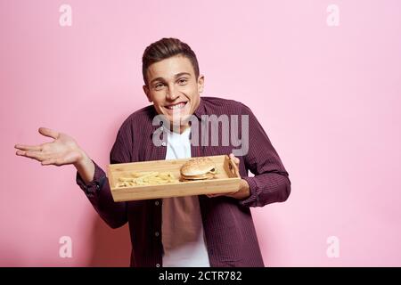 Man with wooden pallet fast food diet food lifestyle pink background Stock Photo