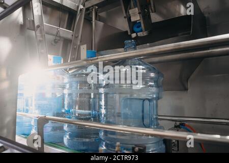 Plastic bottles or gallons on automated conveyor production line. Water factory, toned Stock Photo