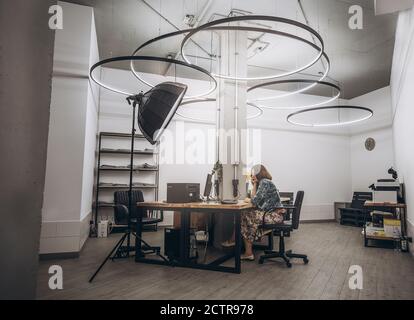 Woman working at desk in a loft office,Pensive business woman sitting at desk with laptop and working on project at loft office on background, led Stock Photo