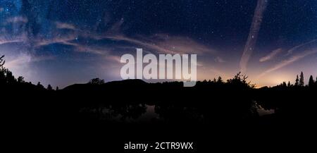 A panoramic view of Tarn Hows with the milky way & the plough shinning through high clouds Stock Photo