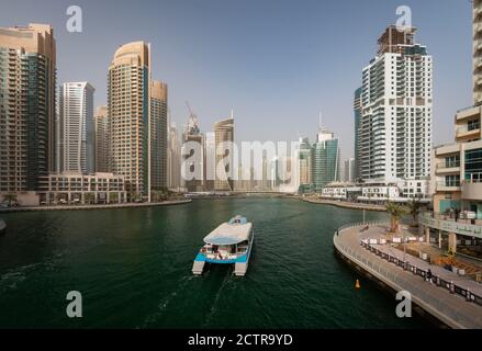 A catamaran-style yacht passes through the marina giving tourists views of the skyscrapers in Dubai, United Arab Emirates (UAE)