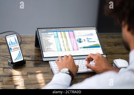 Analyst Employee Using Spreadsheet Software On Phone With External Screen Stock Photo