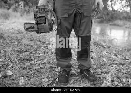 Grayscale shot of a lumberjack with a chainsaw in a forest Stock Photo