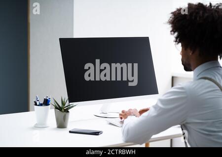African American Working On Computer At Workplace Stock Photo