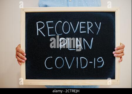 Recovery plan Covid-19. Coronavirus concept. Boy hold inscription on the board. Stock Photo