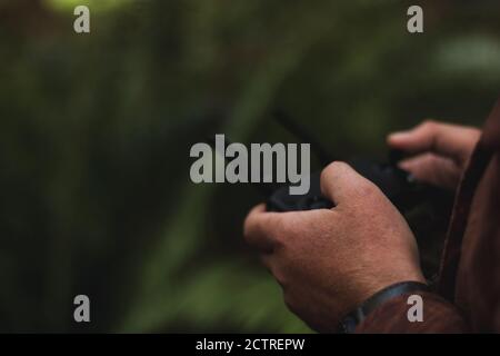 Closeup of mans hands controlling drone remote displaying selective focus of only part of the hand while remote control is defocused. Stock Photo