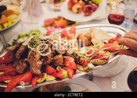 Kebab - grilled meat with french fries and vegetables on wooden background. Stock Photo