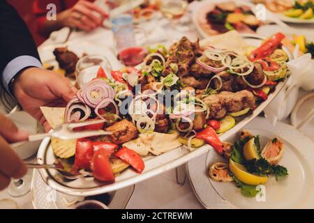 Kebab - grilled meat with french fries and vegetables on wooden background. Stock Photo