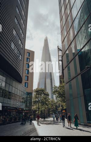London, UK - August 25, 2020: View of The Shard between the buildings on More London, people walking in front. The Shard is are one of the most popula Stock Photo