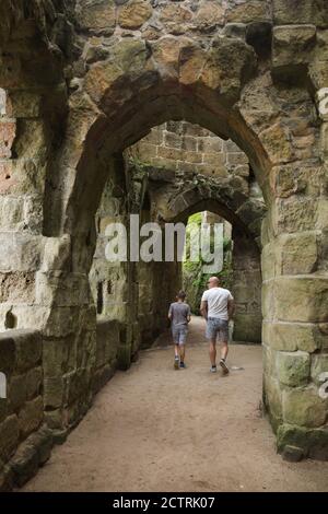Visitors pass through the romantic medieval ruins of the former monastery cloister in the Oybin Monastery in Saxony, Germany. Stock Photo