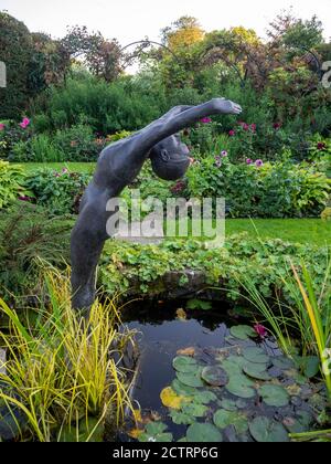Chenies Manor Sunken Garden in mid September 2020. Lily pond with 'The Diver', sculpture by Alan Biggs. Layers of interest, vines and shrubs, dahlias. Stock Photo