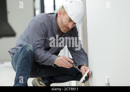 electrician installs paired socket on the wall Stock Photo