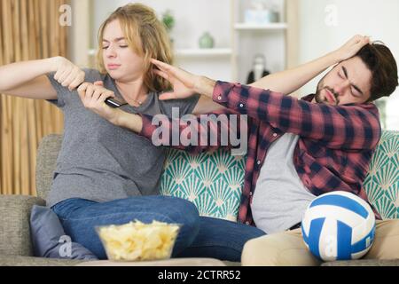 angry couple fighting over tv control remote Stock Photo